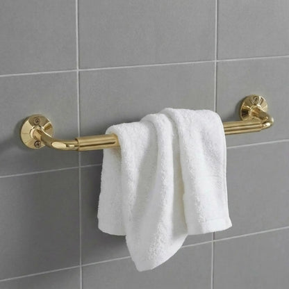 Solid unlacquered brass towel rail mounted on grey tile, featuring a draped white plush cotton towel in a minimalist bathroom setting.